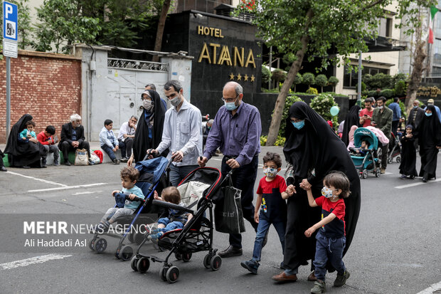 خانواده ای در مراسم راهپیمایی روز جهانی قدس در میدان فلسطین جهت اقامه نماز سمت دانشگاه تهران راهی می شوند