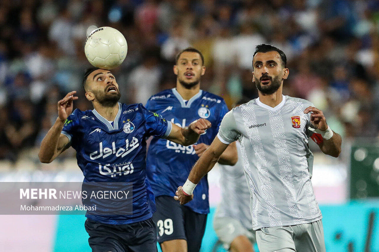 ارسلان مطهری بازیکن تیم فوتبال استقلال تهران در حال عبور توپ از مدافع تیم فوتبال پدیده مشهد در دیدار تیم های استقلال تهران و پدیده مشهد است