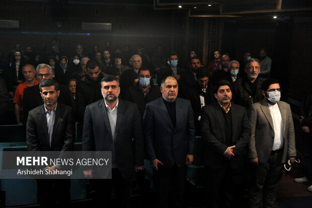 حاضرین در حال ادای احترام به سرود جمهوری اسلامی ایران در مراسم اختتامیه بیستمین جشنواره کتاب و رسانه هستند