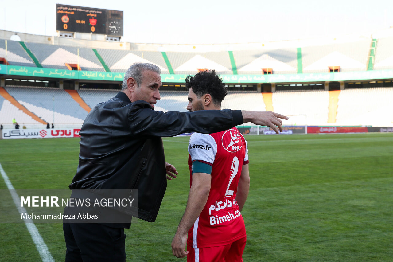 یحی گلمحمدی سرمربی تیم فوتبال پرسپولیس تهران پیش از شروع دیدار تیم های فوتبال پرسپولیس تهران و نفت مسجد سلیمان در حال گفتگو با امید عالیشاه کاپیتان تیم فوتبال پرسپولیس تهران است