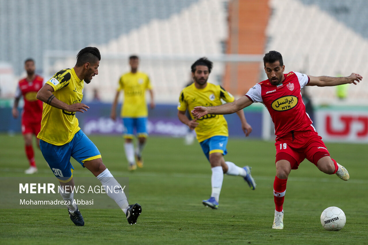 وحید امیری هافک تیم فوتبال پرسپولیس تهران در حال عبور توپ از مدافعین تیم فوتبال نفت مسجد سلیمان در دیدار تیم های فوتبال پرسپولیس تهران و نفت مسجد سلیمان است